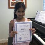 Here's an alt tag for the image: Smiling girl holding music achievement award.