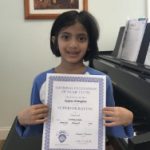 Here's an alt tag for the image: Smiling girl holding superior rating certificate.