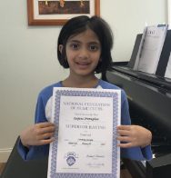 Here's an alt tag for the image: Smiling girl holding superior rating certificate.