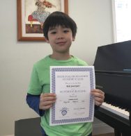 Here's a short alt tag for the image: Smiling boy holding music achievement certificate.